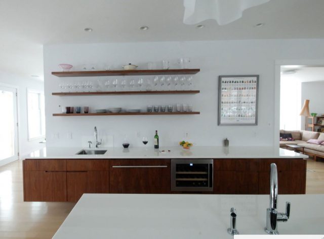 Dark wooden open shelves in a white kitchen