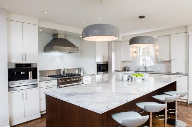 Large pendant lamps over an island in a white kitchen